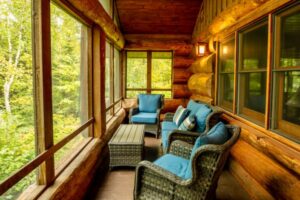 Inside of 3 seasons porch in Cabin 11 with wicker chairs and blue cusions