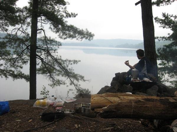 Man at campsite with food overlooking still lake