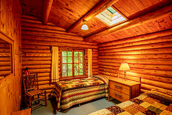 Bedroom of log cabin with slanted roof, a sunlight and two twin beds