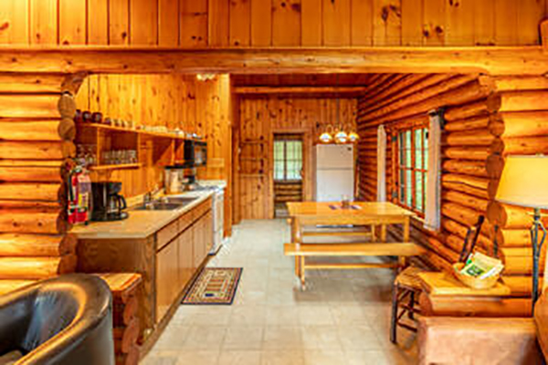 Dining room and kitchen in log cabin with picnic style table