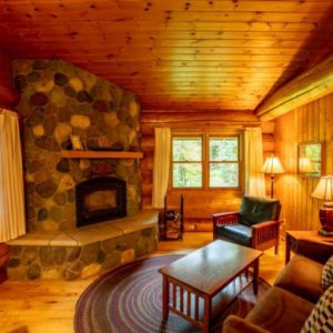 Stone fireplace in log cabin with brown couch