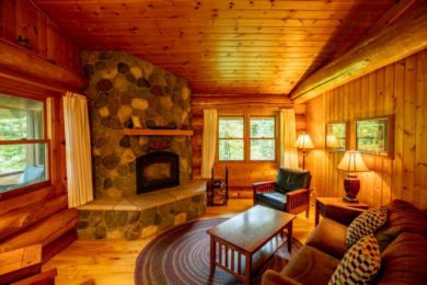 Stone fireplace in log cabin with brown couch