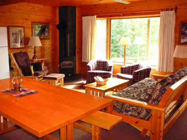 Otter Lodge living area with plaid chairs and patterned couch as well as picnic style dining table