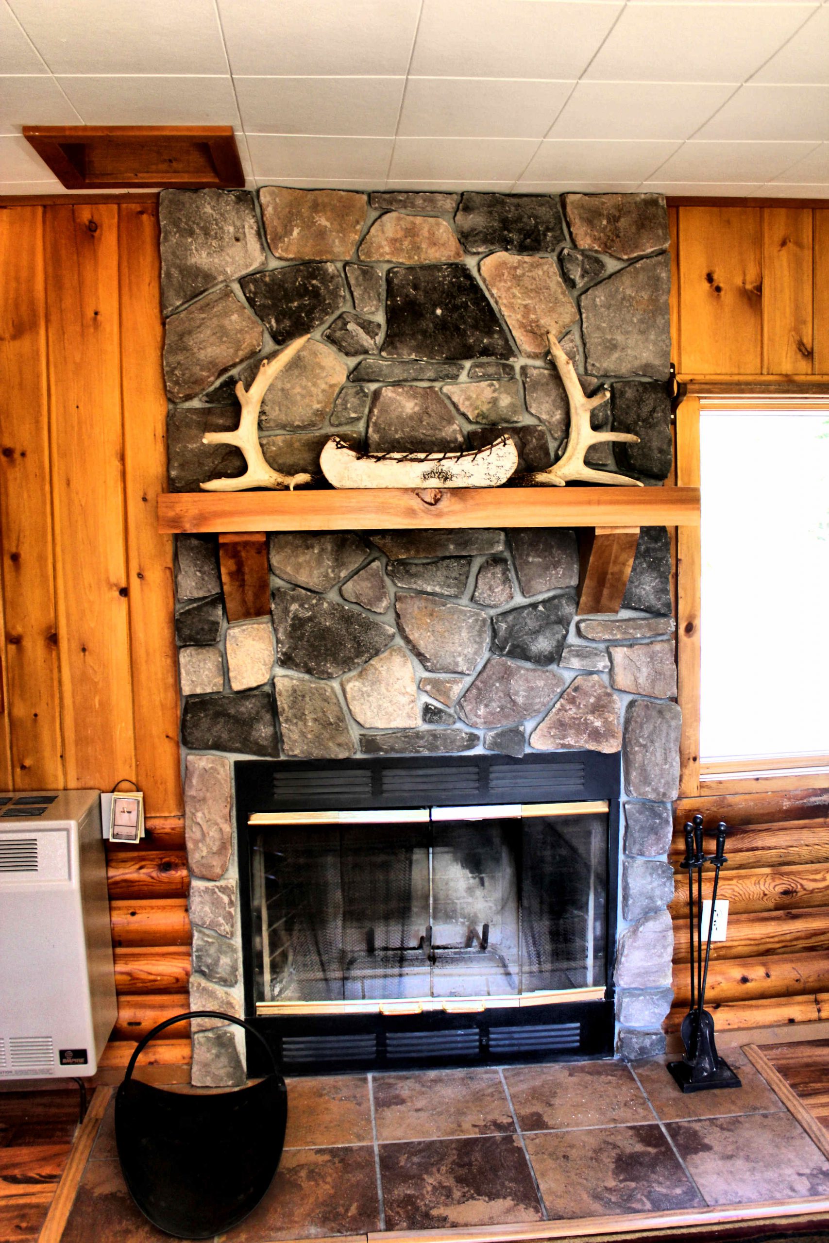 Stone fireplace in a log cabin with antlers on mantle