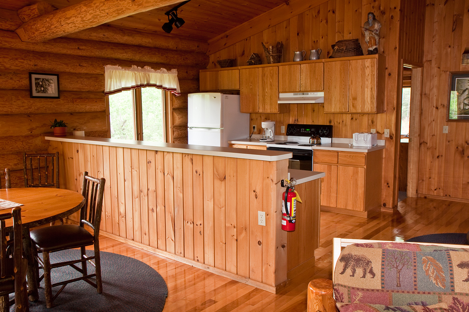 Kitchen area of log cabin with wooden cabinets and white fridge