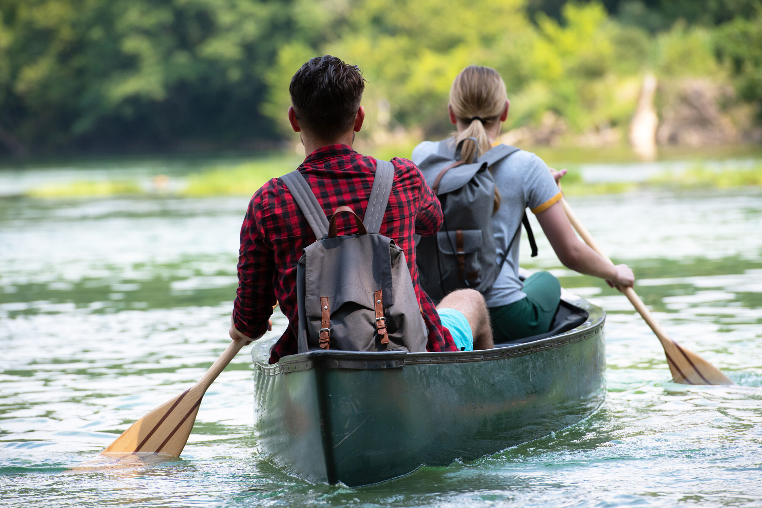 A shot from behind of a man and woman canoeing together on a river